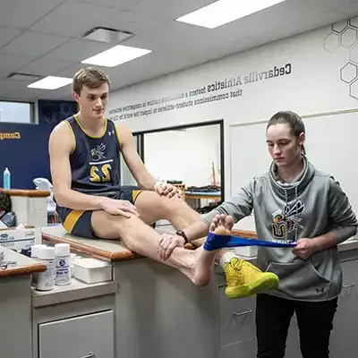 student athletic trainer treating athlete.