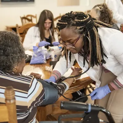 Female nursing student working with a senior female patient.